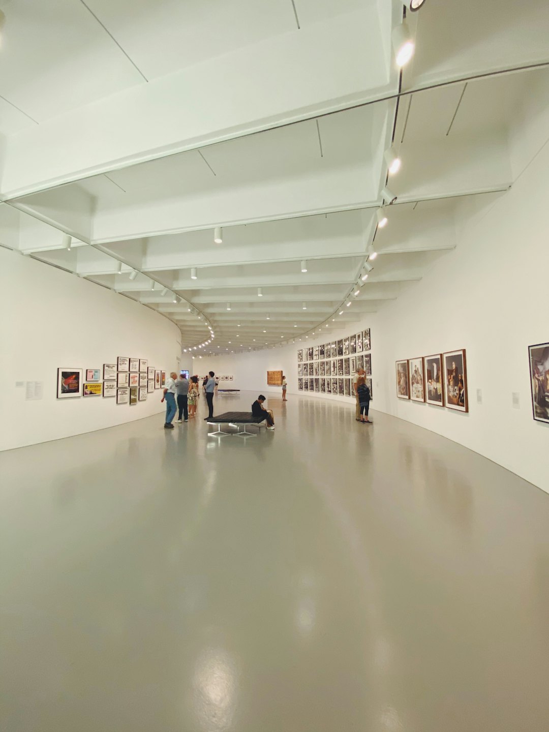 Visitors examine art in a bright, modern gallery.
